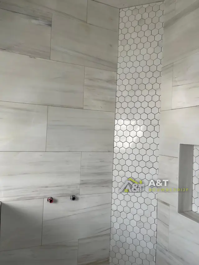 Hexagon-mozaïek in de douche. Wandtegels met een strook hexagon-mozaïek, vóór montage van de kranen.