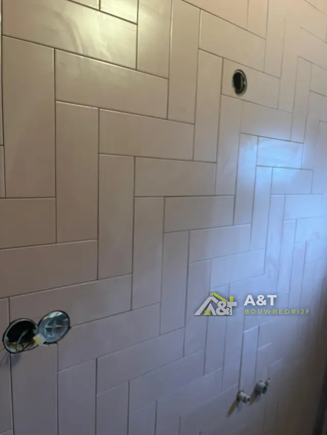 Witte visgraat op de wand. Wandtegels in visgraatpatroon, vóór het plaatsen van kranen en sanitair.